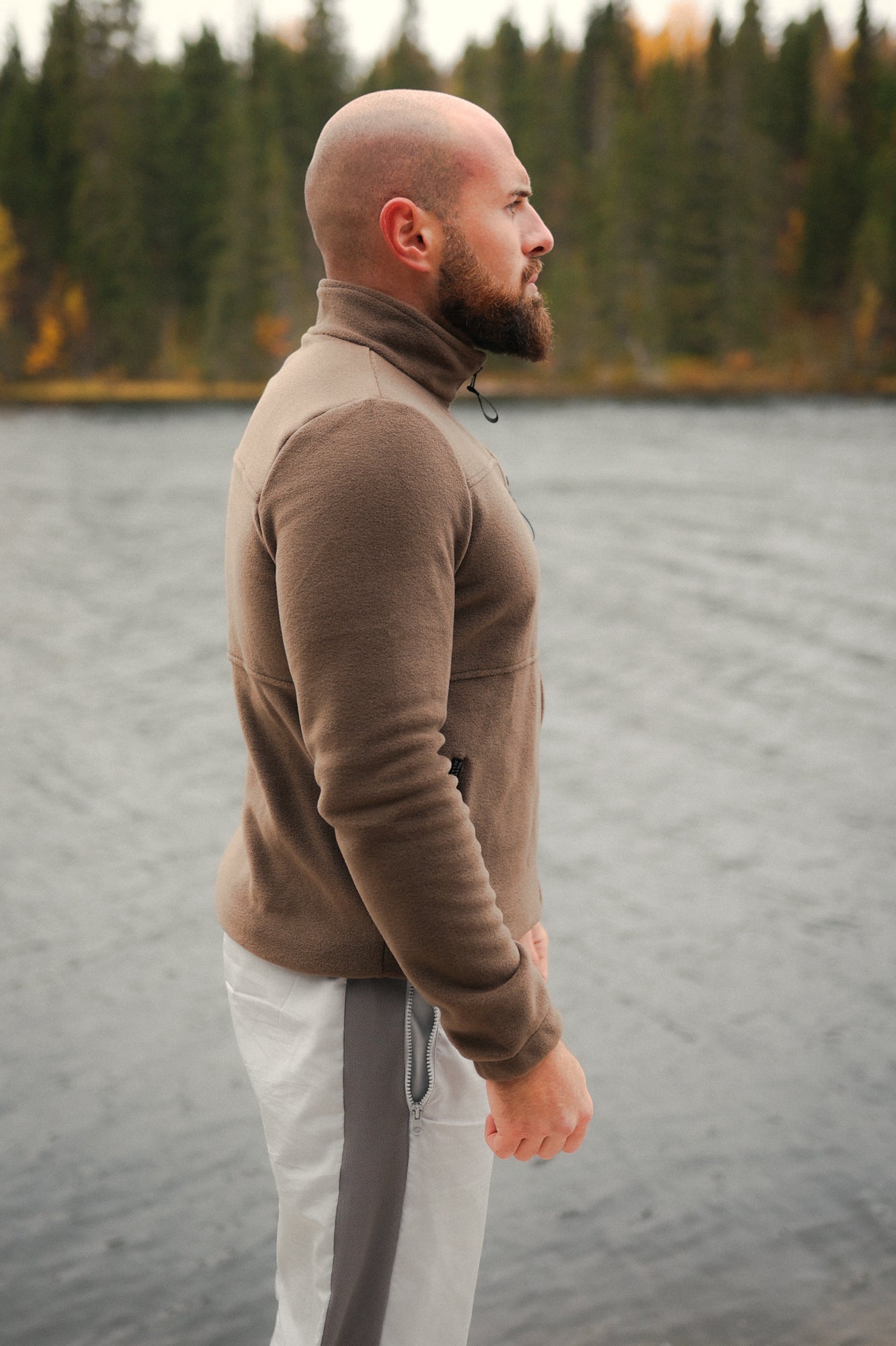 Brown Avantura fleece jacket with high collar and zipper, worn by man outdoors