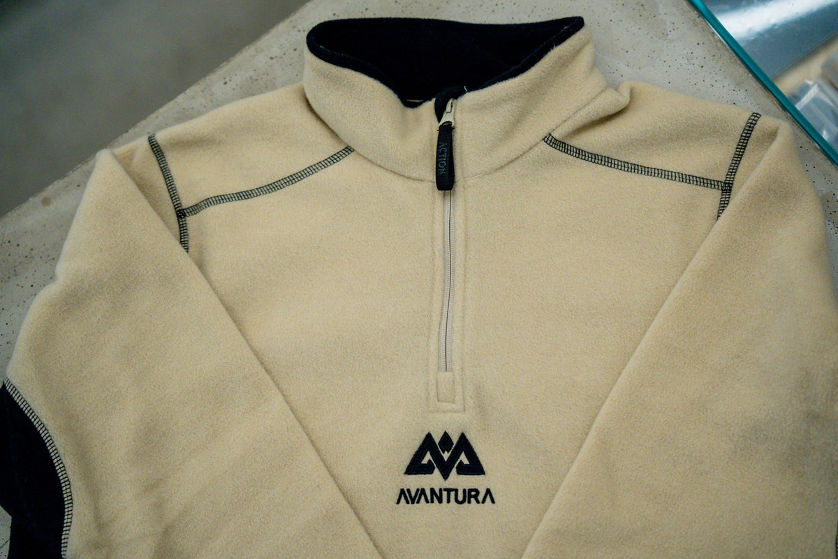 Detail view: High collar and quilting stitch on beige-black half-zip fleece