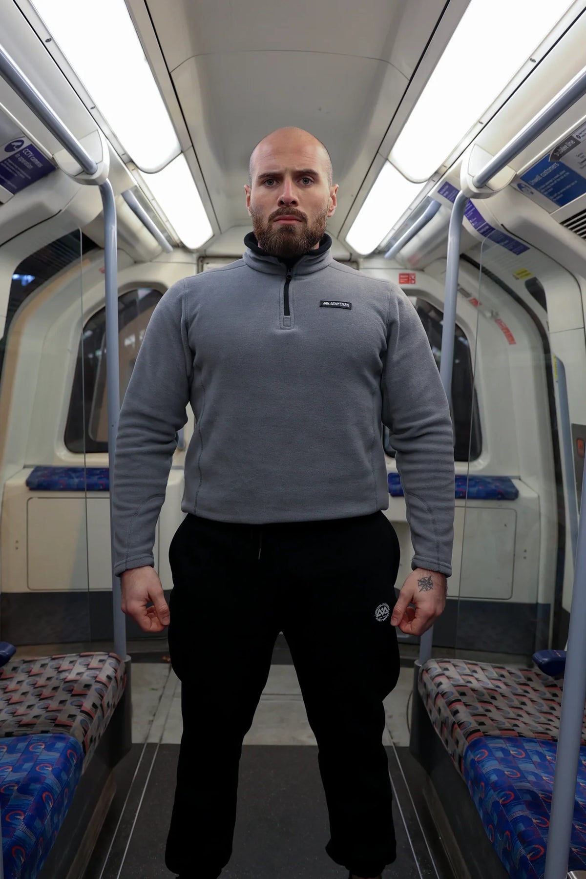 Man standing in grey halfzip fleece pullover, displaying front design and loose fit