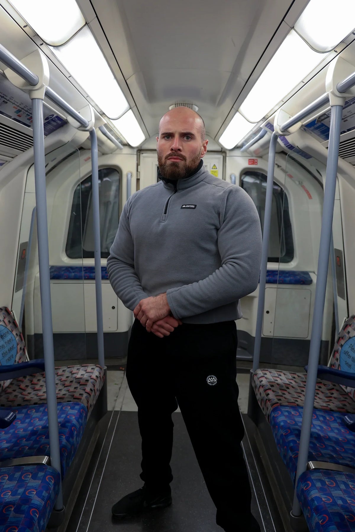 Full body view of man in grey halfzip fleece pullover on subway, highlighting relaxed fit