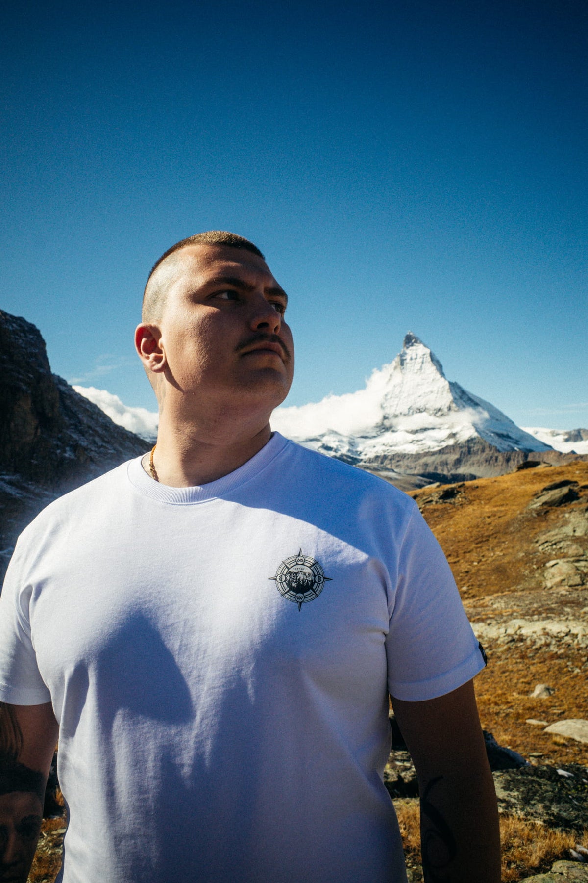 White Avantura T-shirt with compass logo on chest, worn during outdoor activities