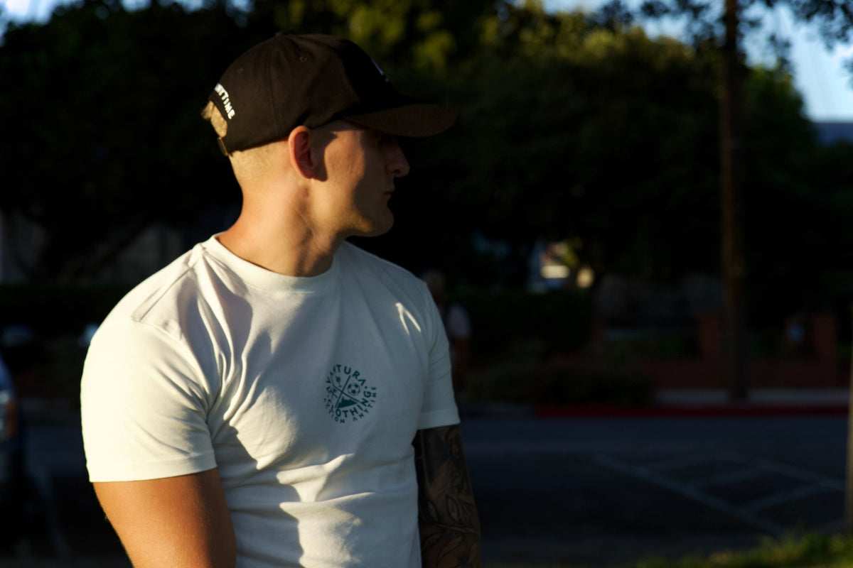 Close-up of beige t-shirt chest logo detail, highlighting fabric texture and small icon design