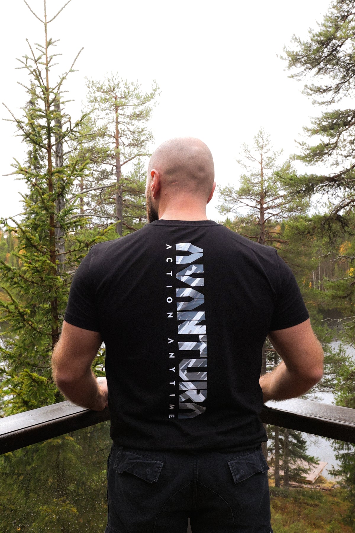 Mann im schwarzen T-Shirt mit Backprint an Holzterrasse