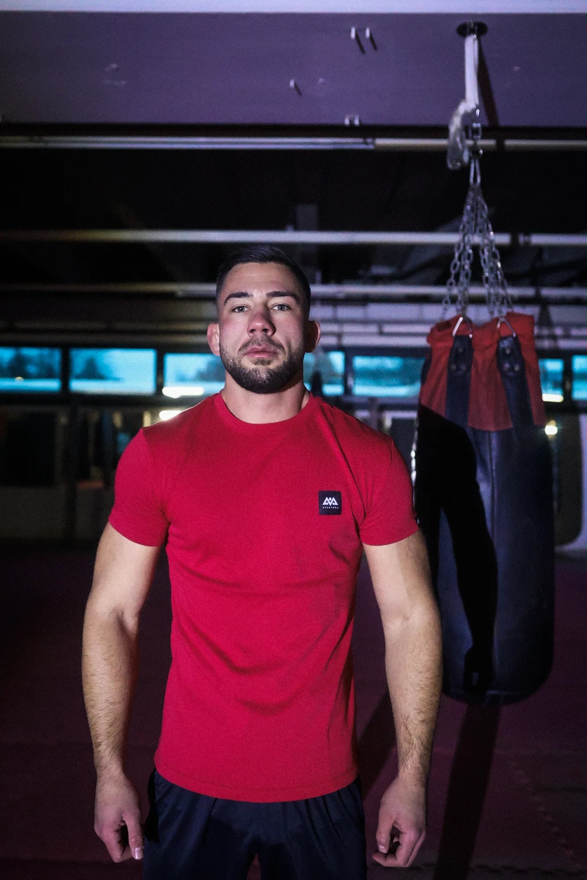 Man wearing fitted red t-shirt with chest patch in gym