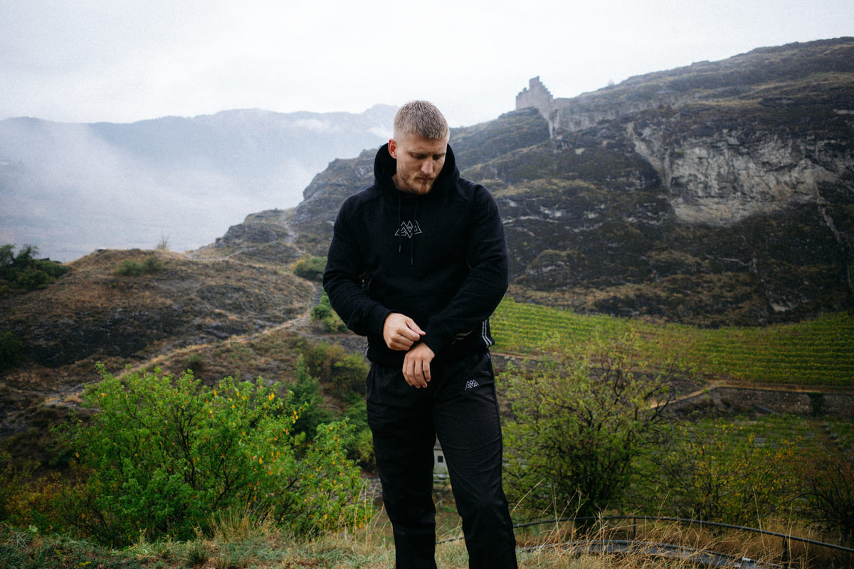 Adjusting sleeves on black hoodie with small geometric logo