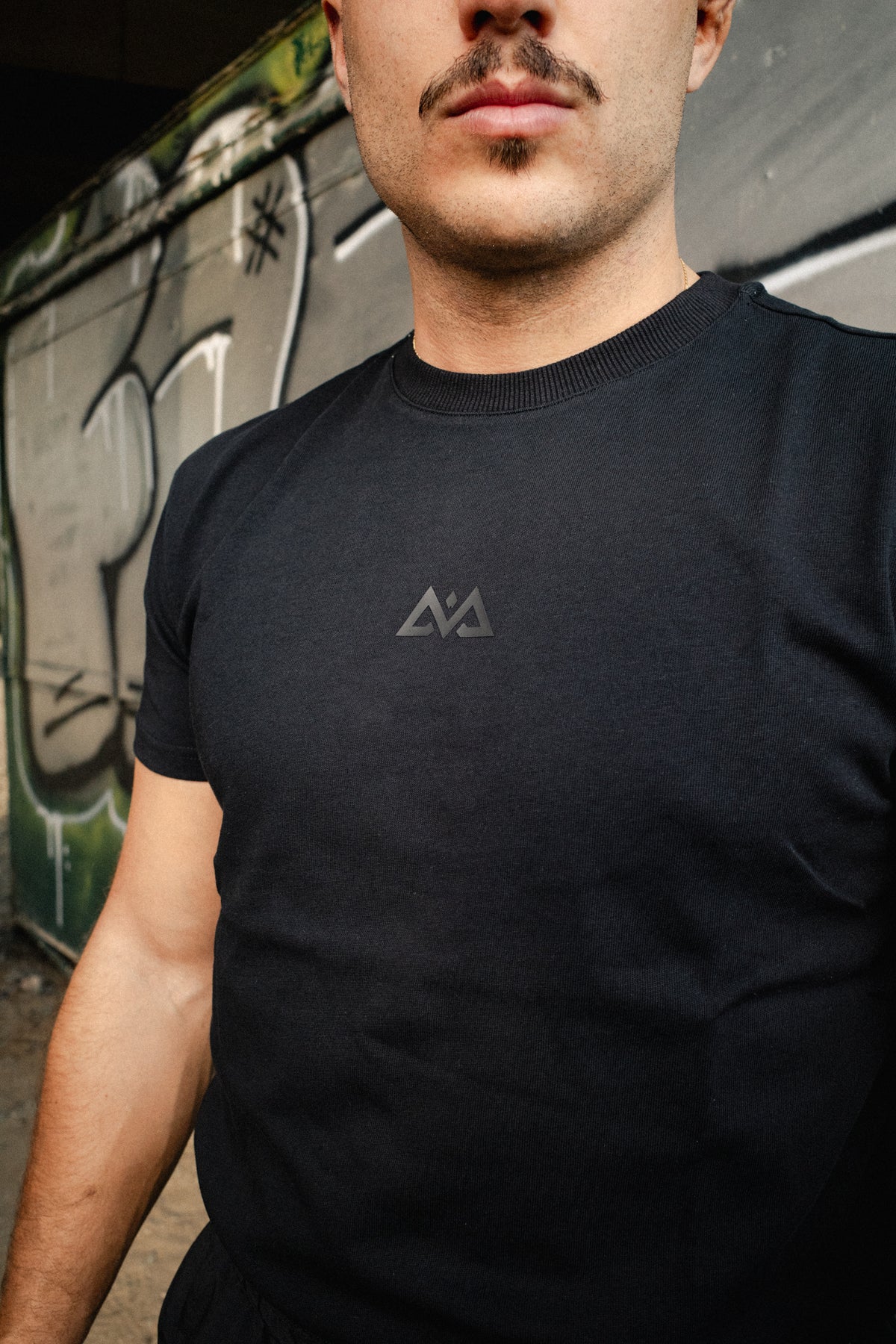 Schwarzes T-Shirt mit Rundhalsausschnitt und kleinem grauem Logo auf der Brust