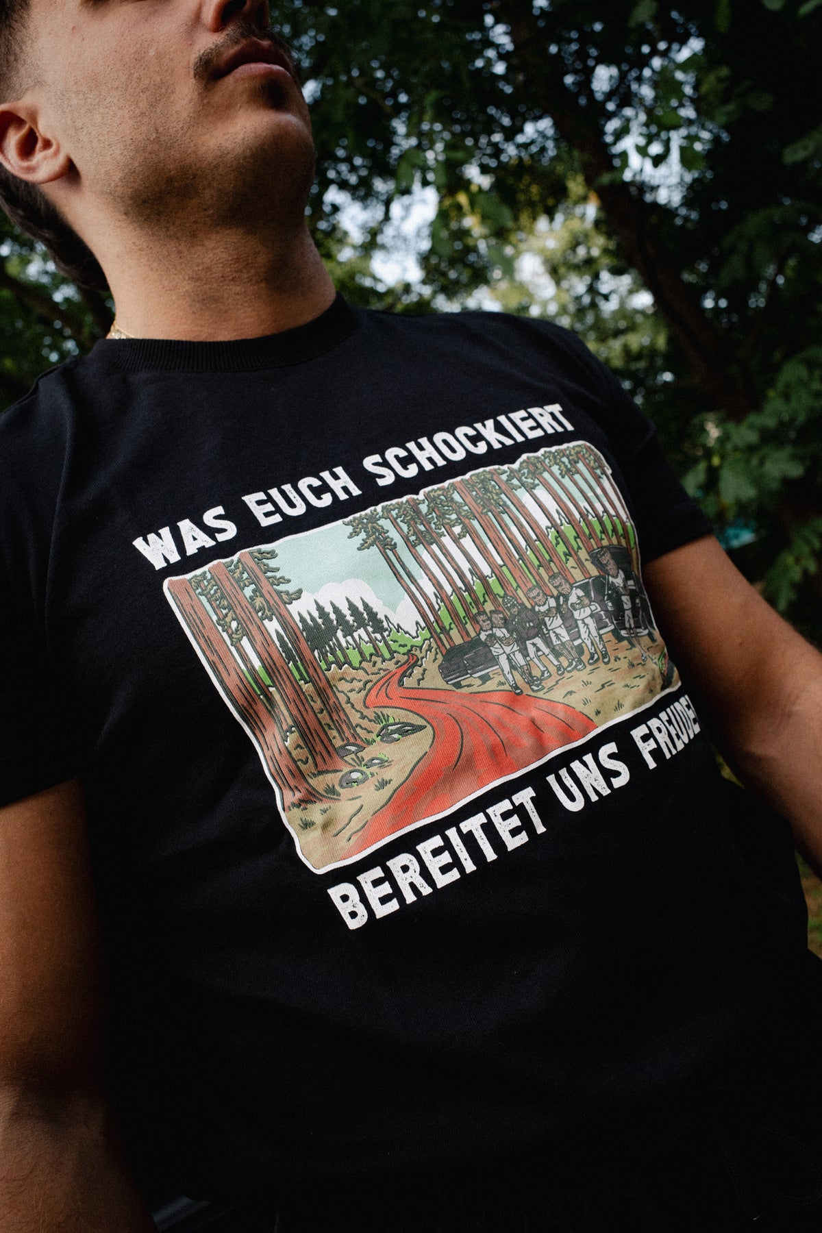 Close-up of black T-shirt chest graphic showing red path through forest