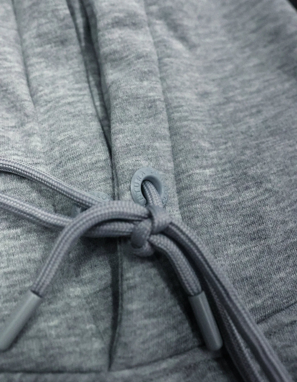 Macro shot of metal eyelet grommet and knotted braided drawstring on grey hoodie neckline