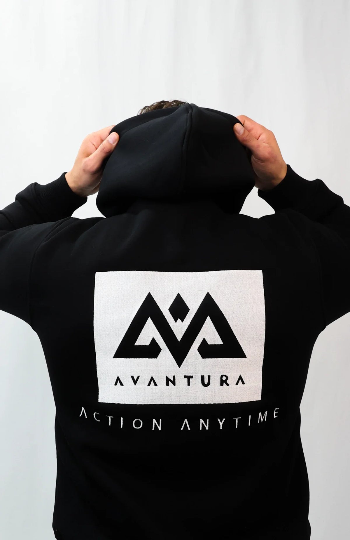 Back of black hoodie showing woven label and 'Action Anytime' print