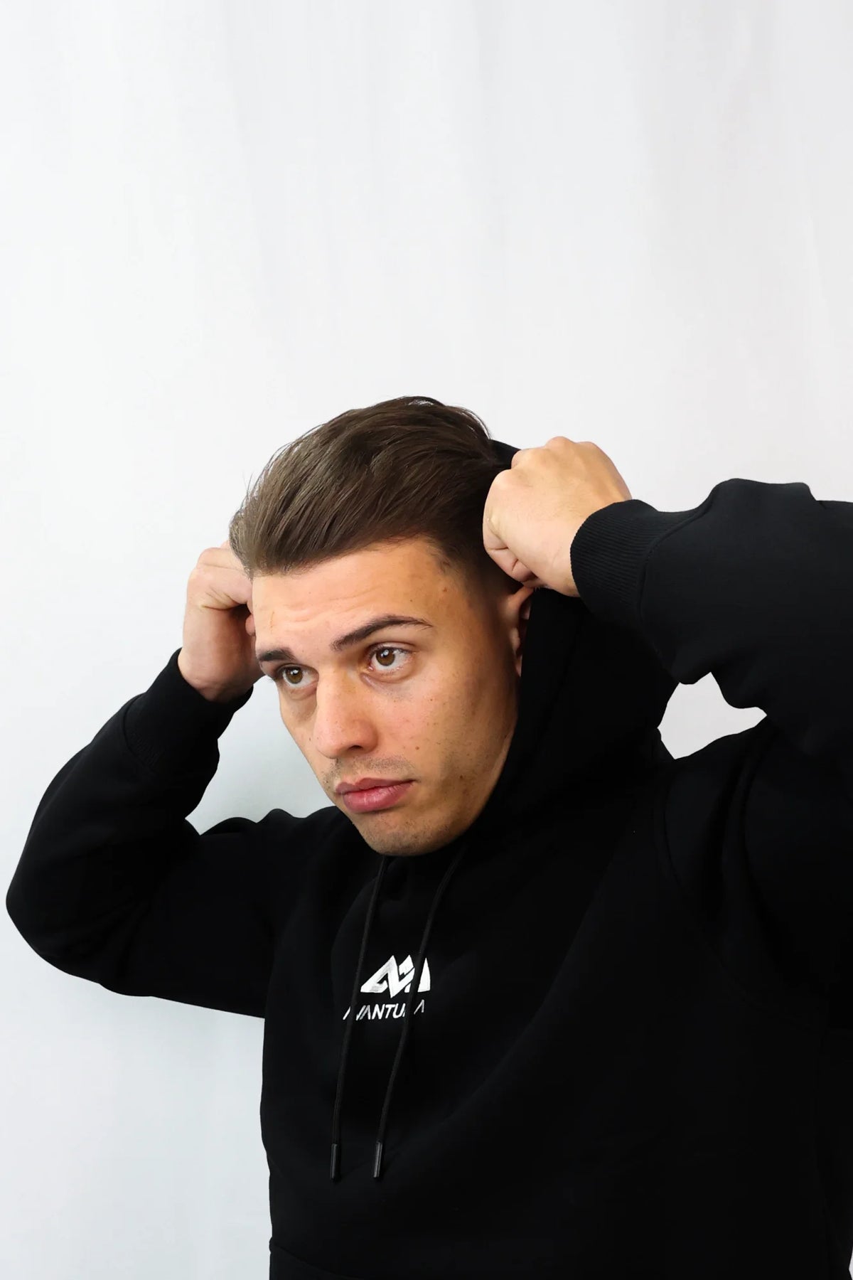 Model adjusting hood on black Avantura clothing sweatshirt