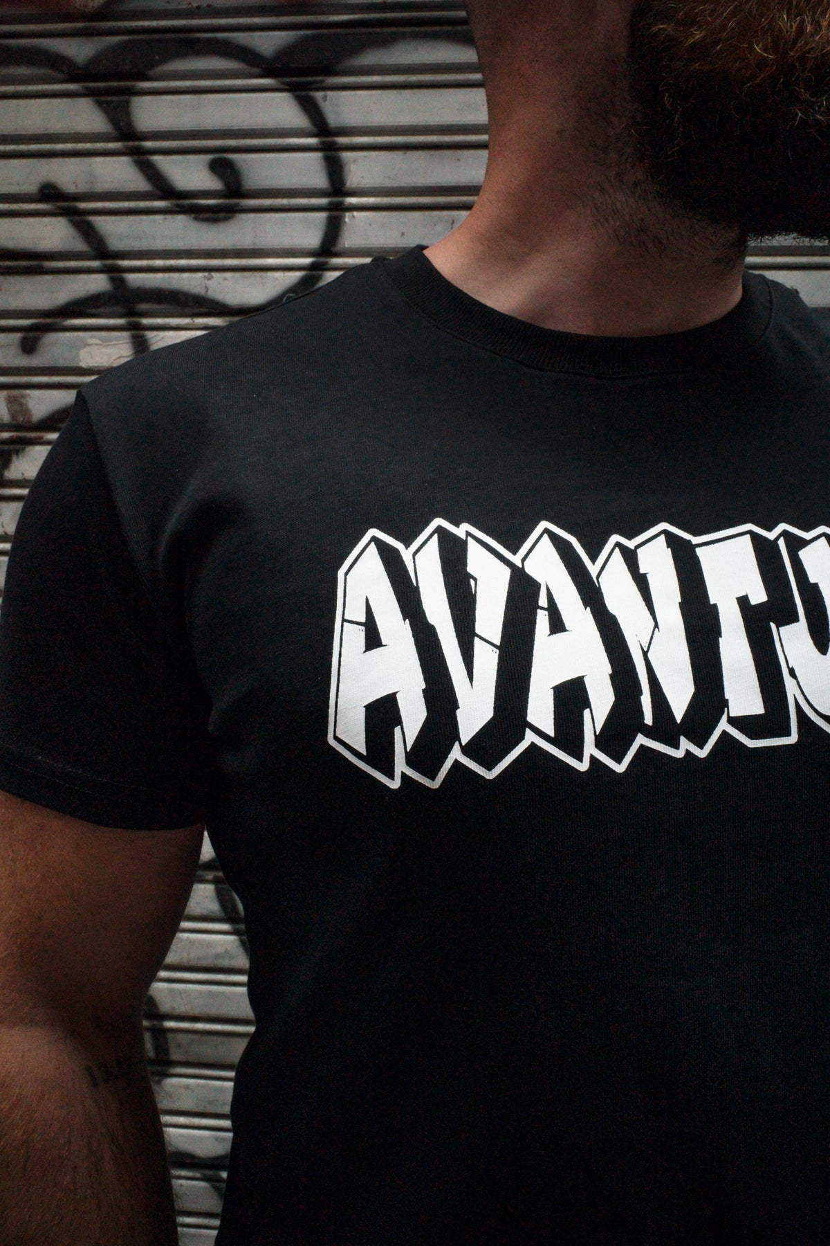 Front neckline detail of black cotton T-shirt with jagged white logo