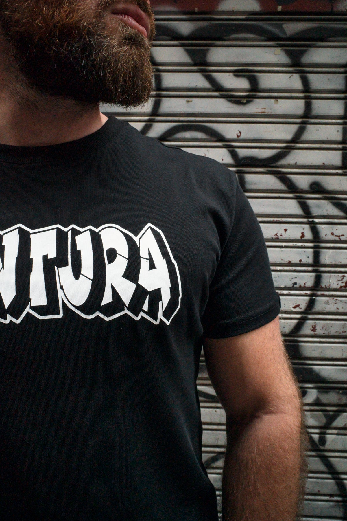 Side angle close-up of black T-shirt chest area and white logo detail