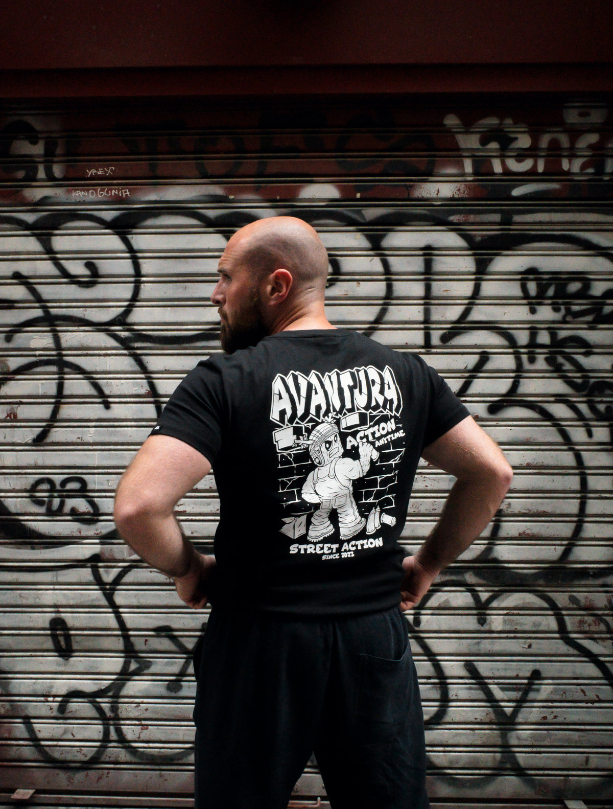Black T-shirt back graphic with mummy character breaking through brick wall