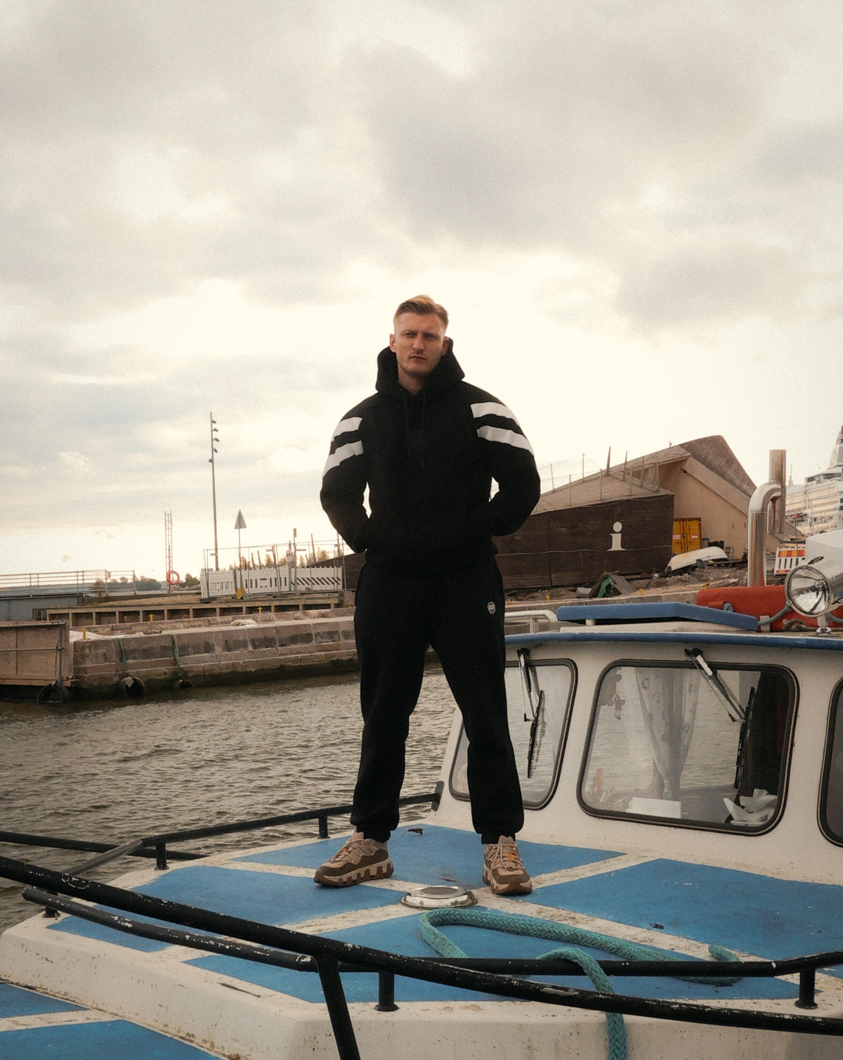 Schwarzer Hoodie mit weißen Streifen am Hafen getragen