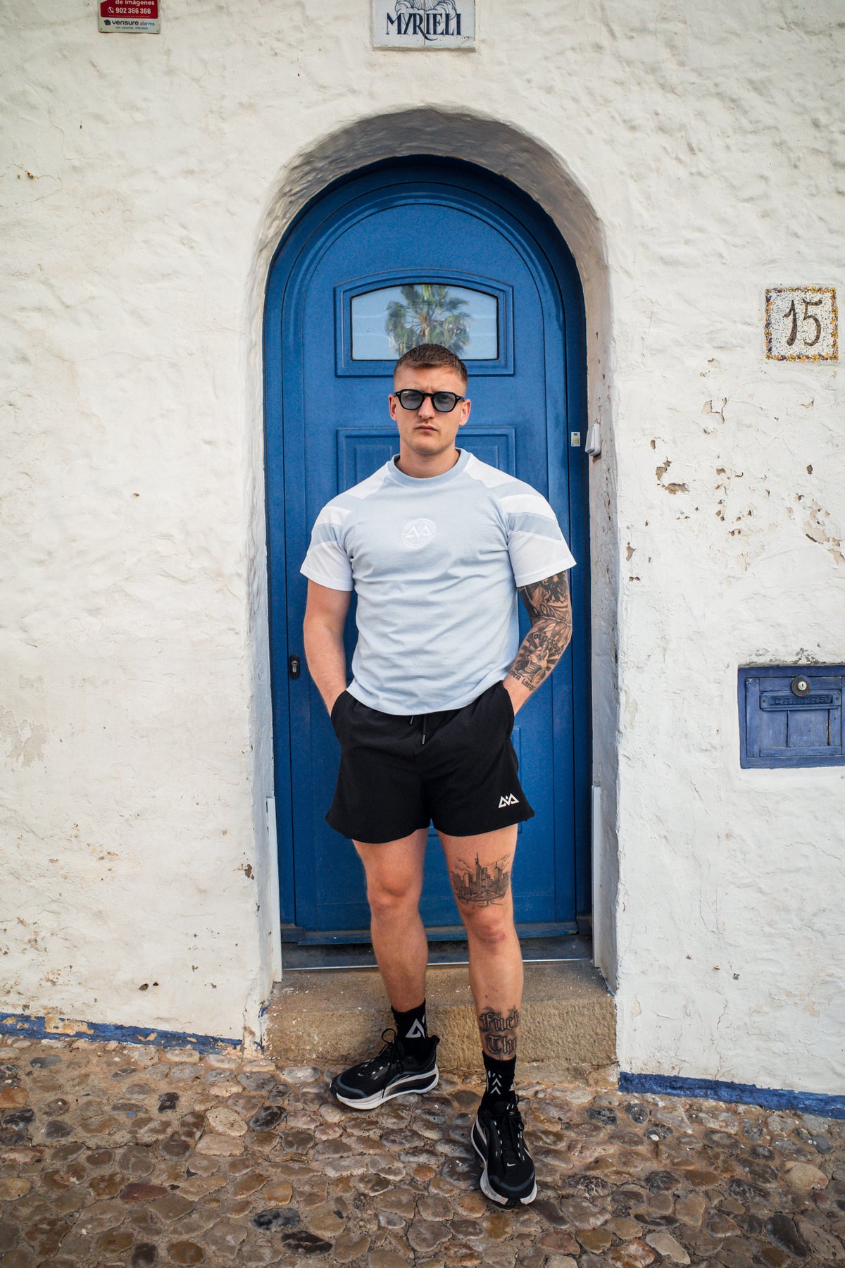 Full body look at light blue striped t-shirt with black sneakers and accessories