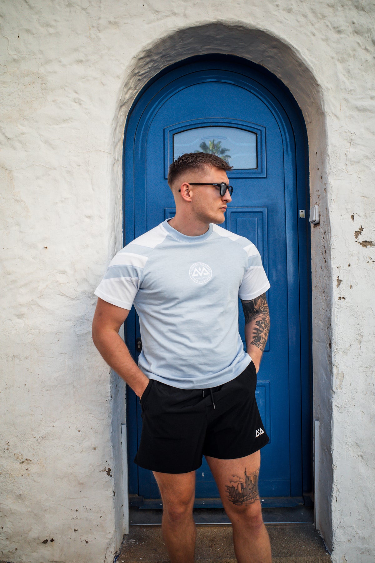Profile view of light blue striped t-shirt with relaxed fit against blue door