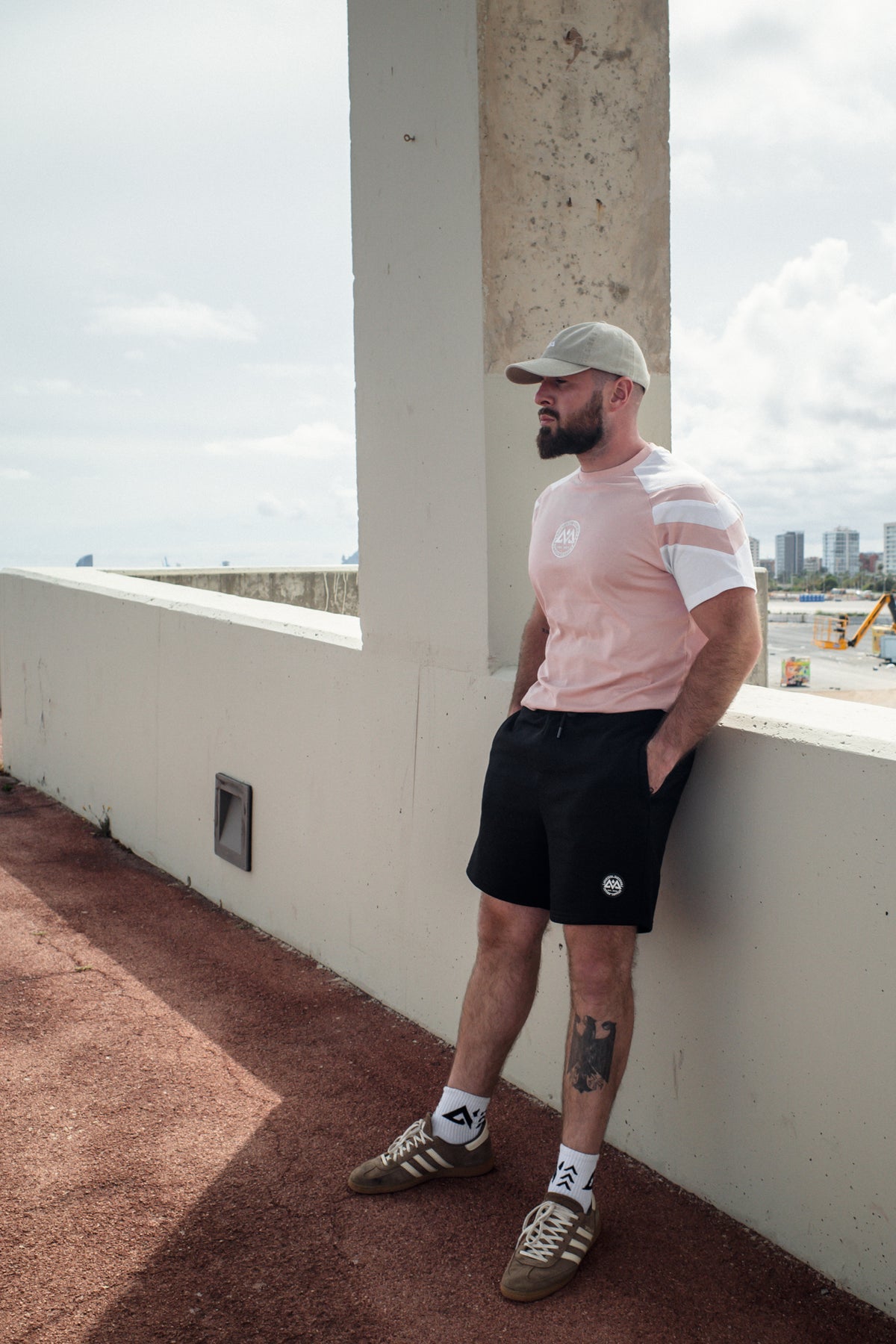 Mann im lockeren rosa Streifen-T-Shirt mit Logo an der Mauer