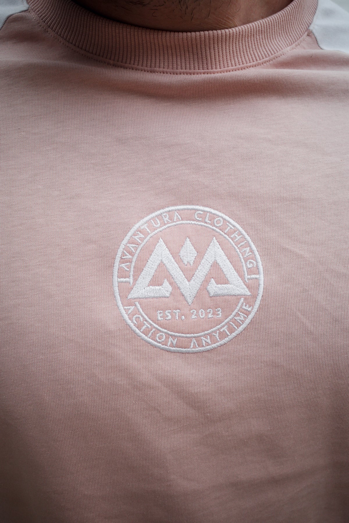 Nahaufnahme gesticktes AVANTURA Logo auf rosa T-Shirt Brust