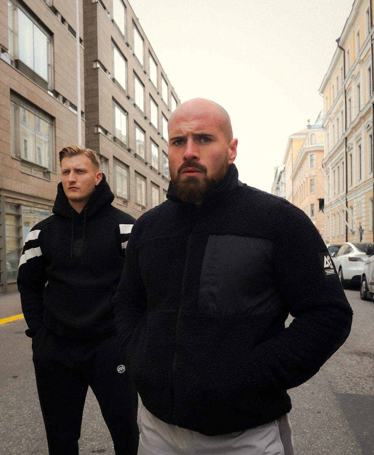 Man wearing black fleece jacket with chest panel and logo patch in city setting