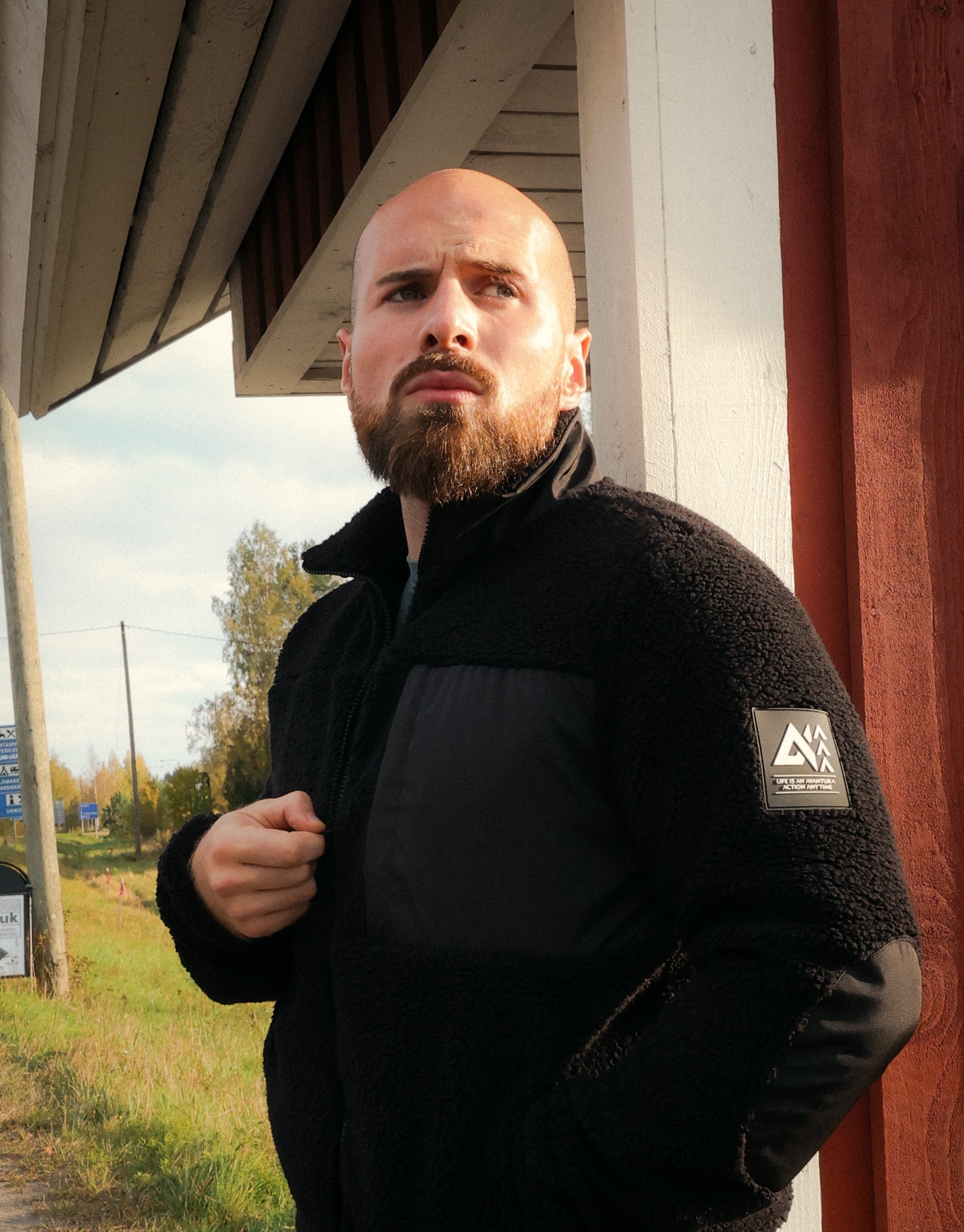 Black teddy fleece jacket with zippered front and logo patch on arm