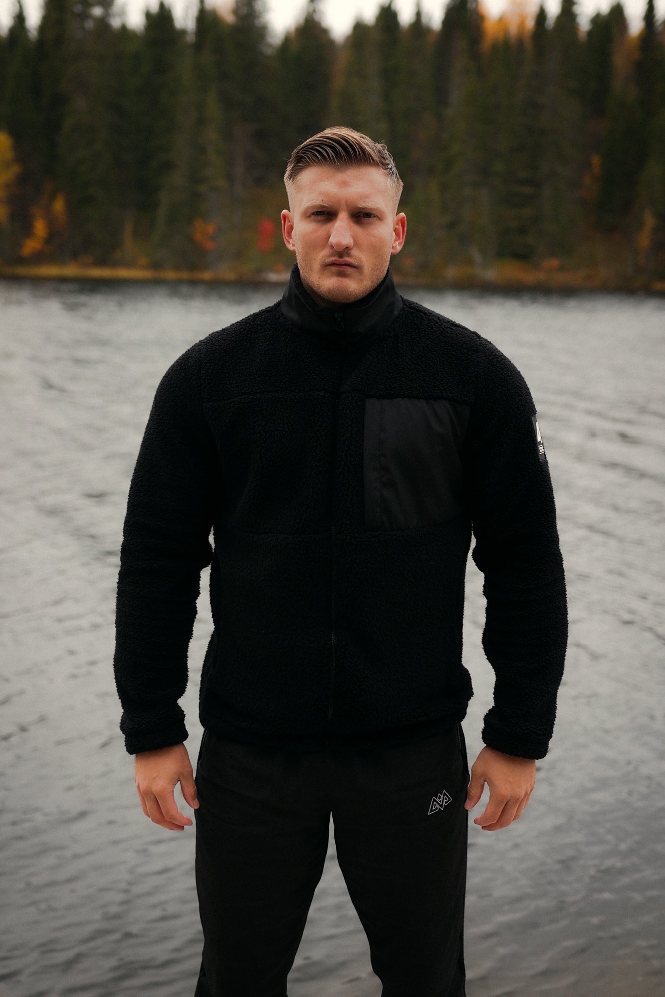 Front view of black full-zip teddy fleece jacket with chest panel and logo