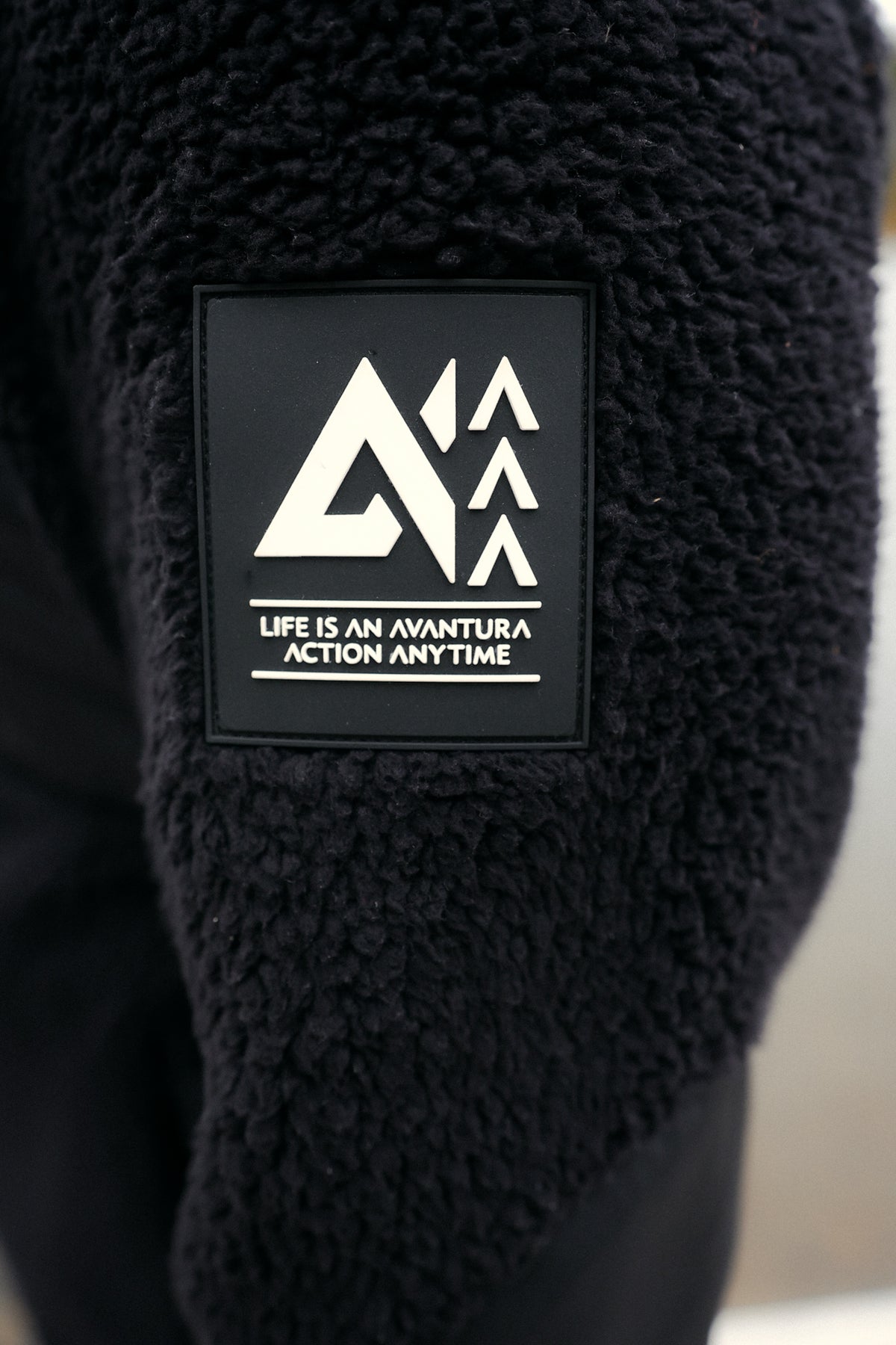 Black rubber logo patch on sleeve reading 'Life is an Avantura' text