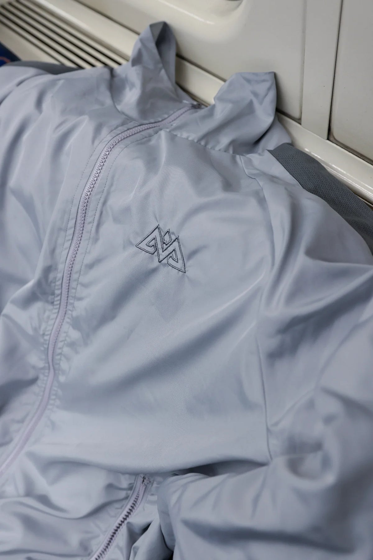 Close-up of embroidered logo on grey trackjacket chest
