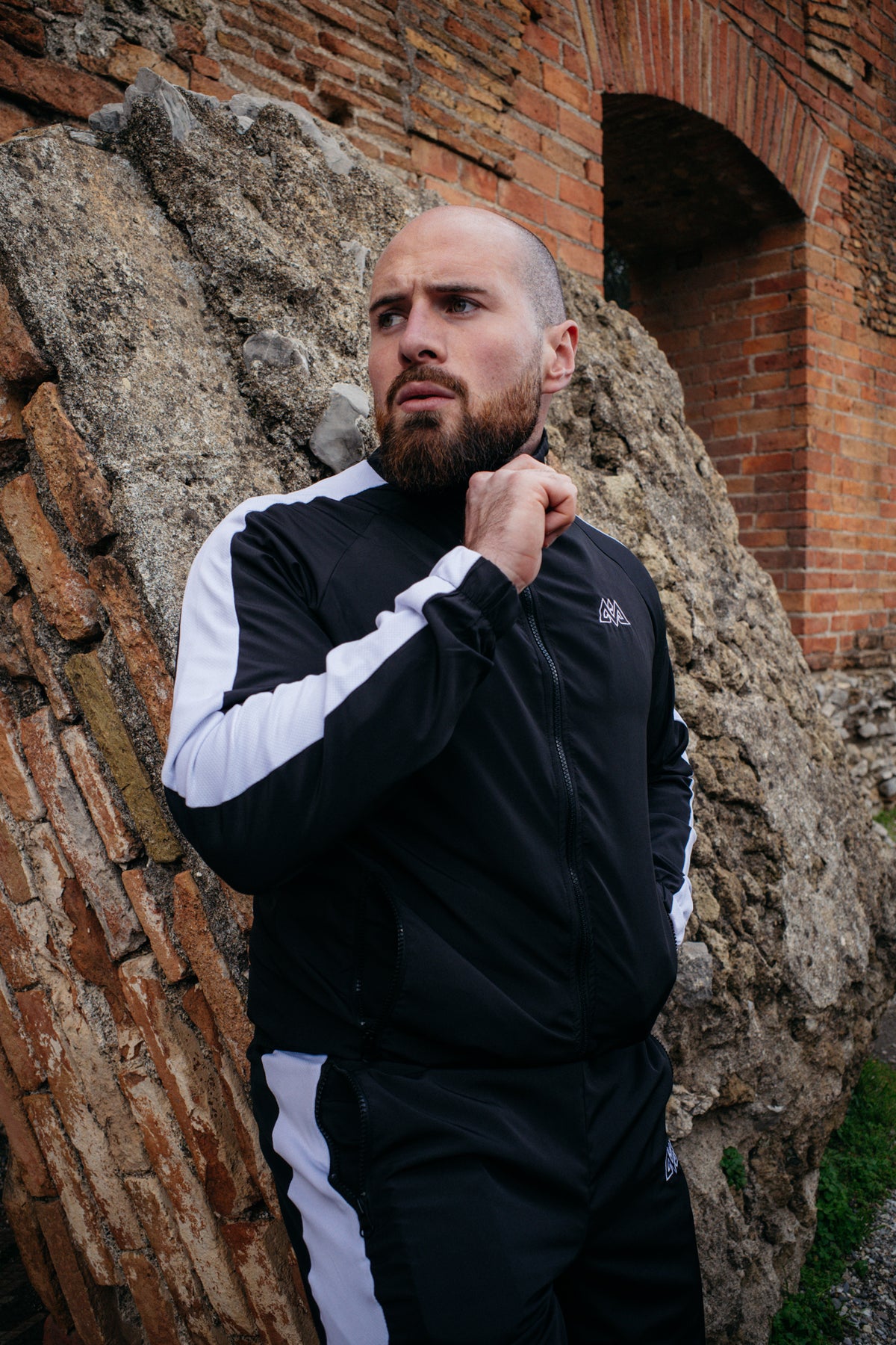Passform der schwarz-weißen Trackjacke an einer Steinmauer