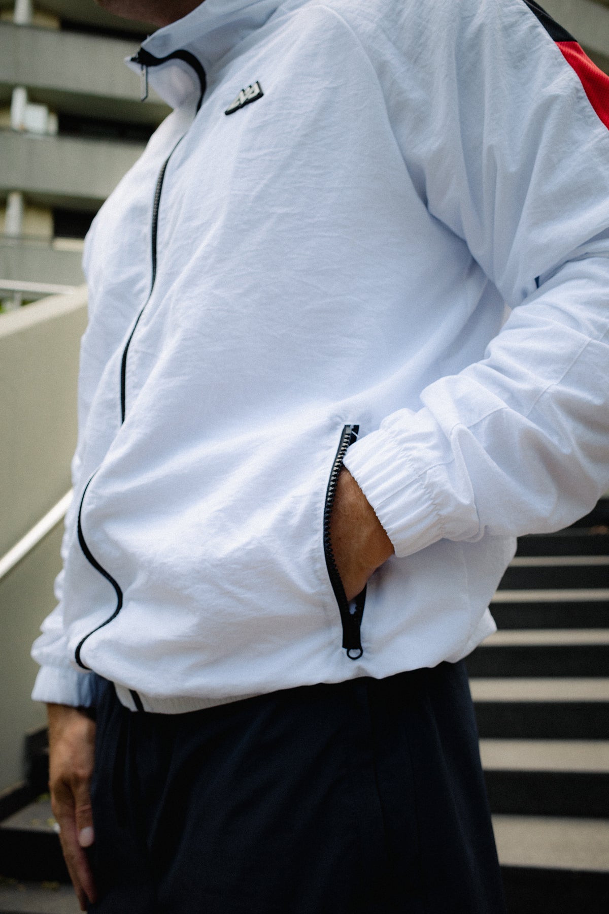 White track jacket side pocket detail with rubber logo