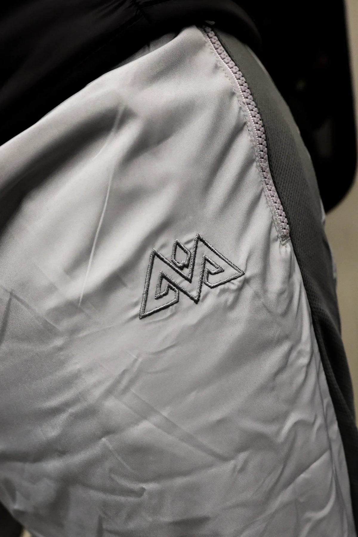 Detail des gestickten Logos an der grauen Trackpants