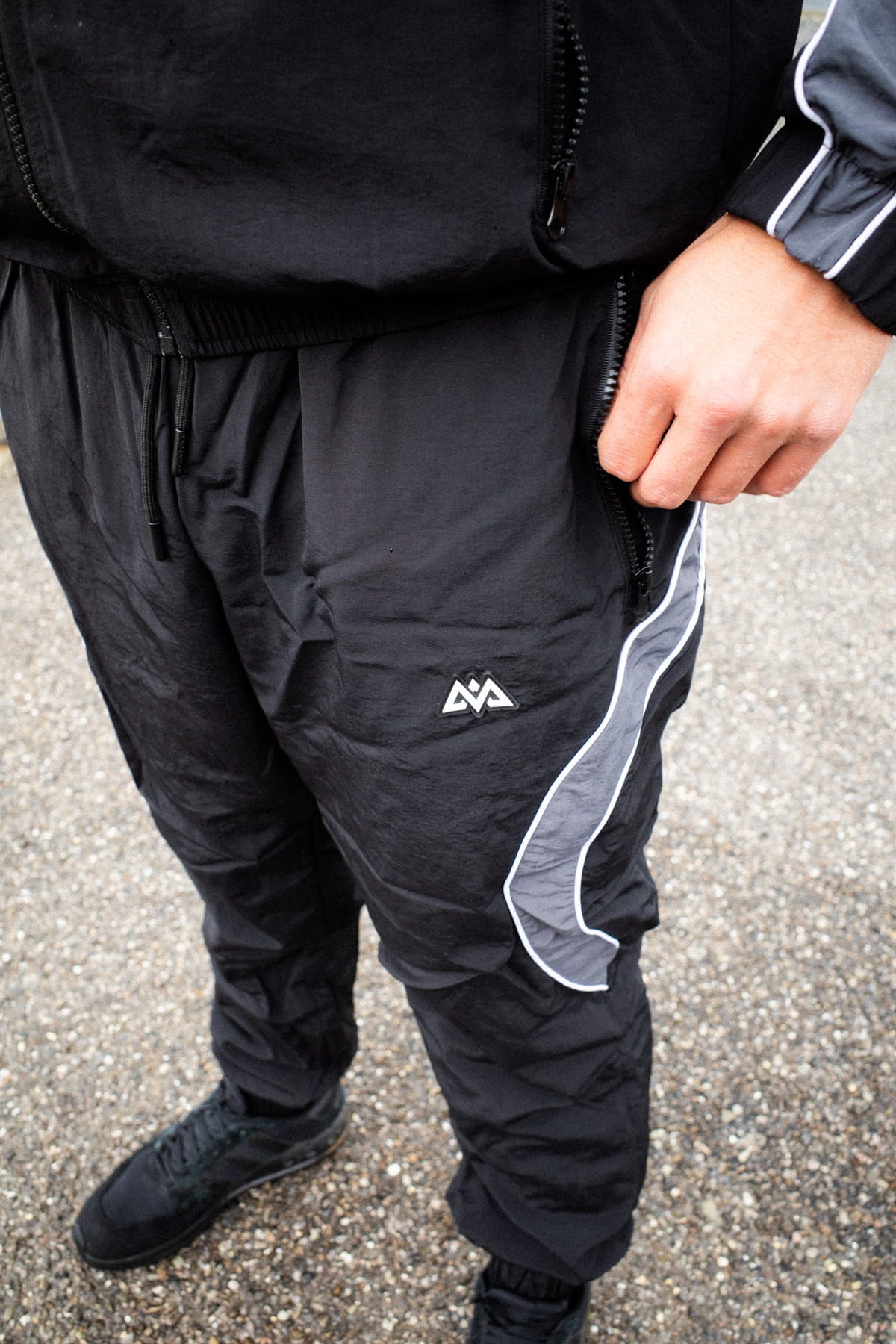 Nahaufnahme der schwarzen Trackpants mit Logo und Tasche