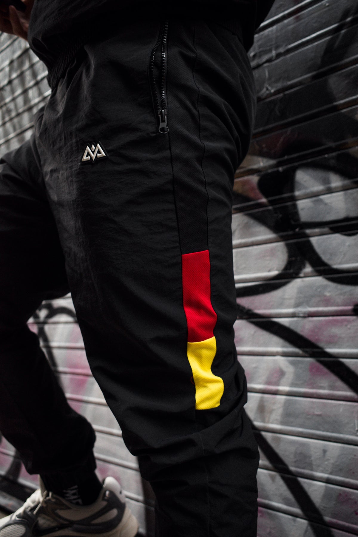 Close-up of black trackpants logo and side stripe
