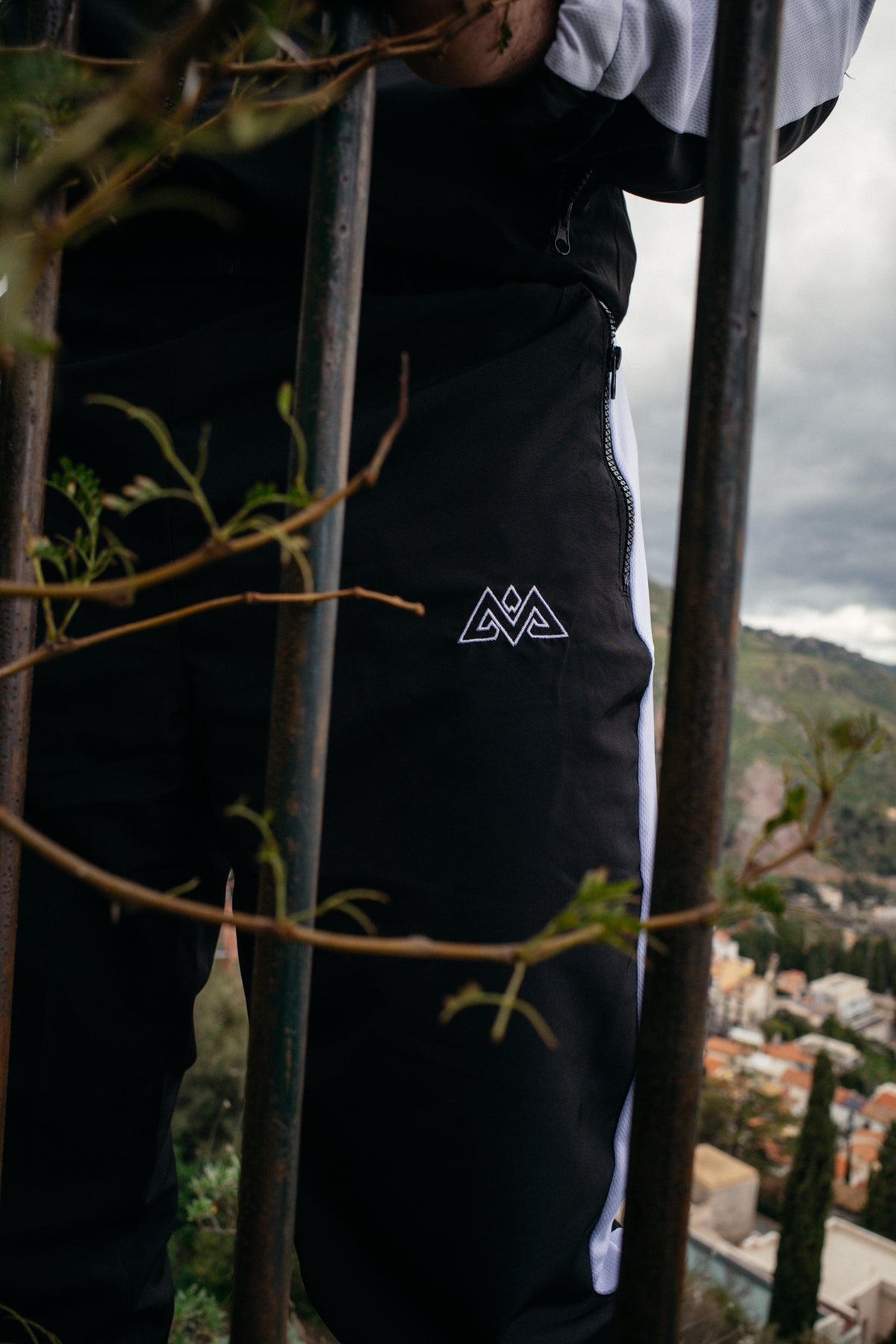 Nahaufnahme: Gesticktes Logo und Reißverschlusstasche an der schwarzen Trackpants