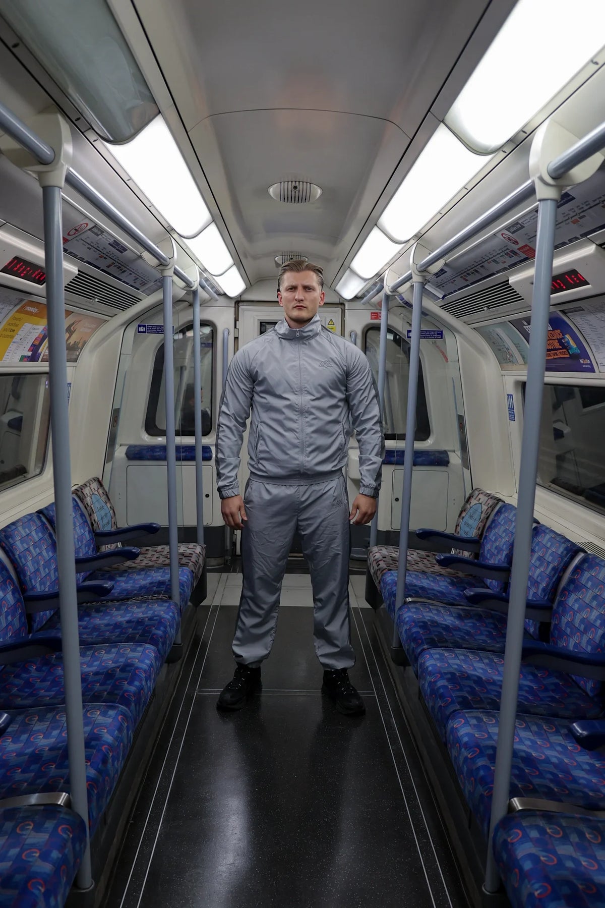 Mann in grauem AVANTURA Trainingsanzug in der U-Bahn