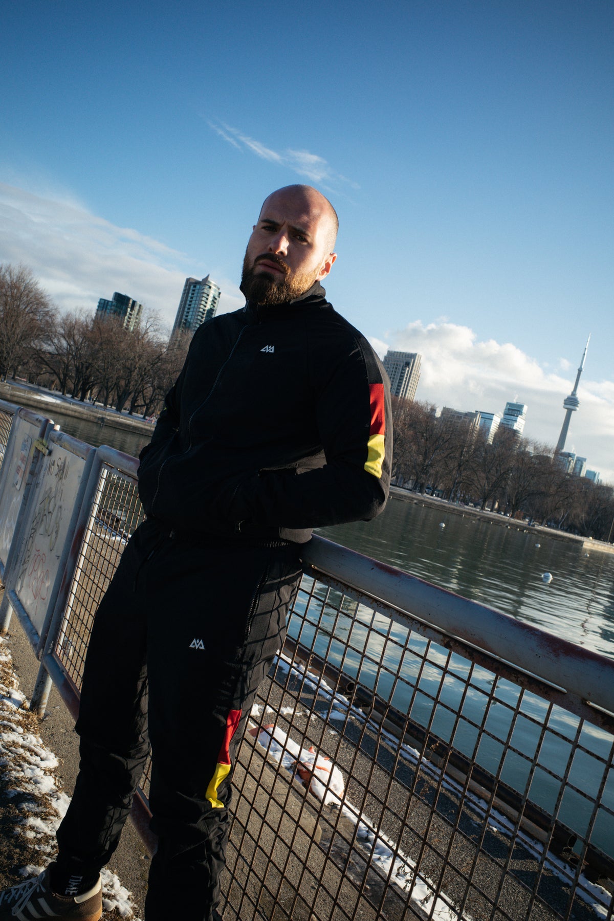 Schwarzer Tracksuit mit rot-goldenen Streifen, städtische Skyline Kulisse