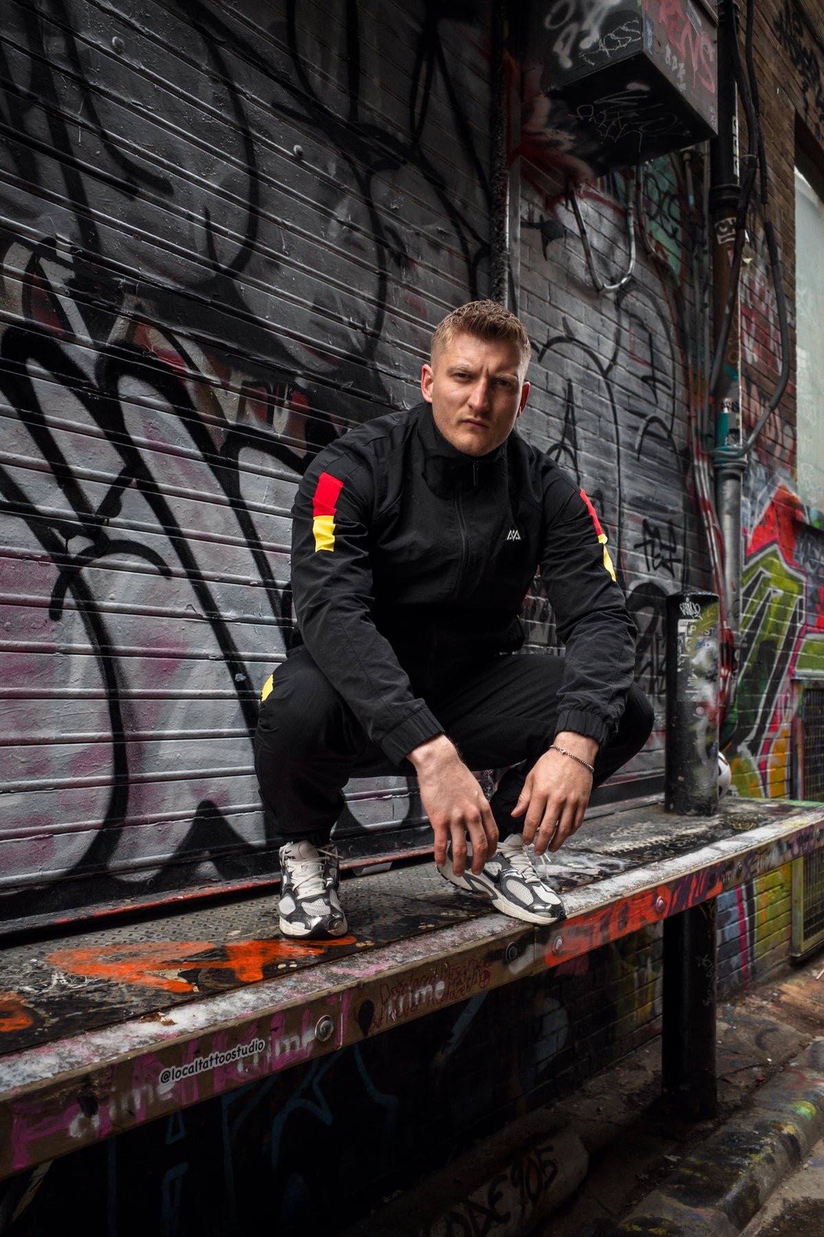 Schwarzer Tracksuit mit roten und goldenen Details, Graffiti-Wall Urban Style