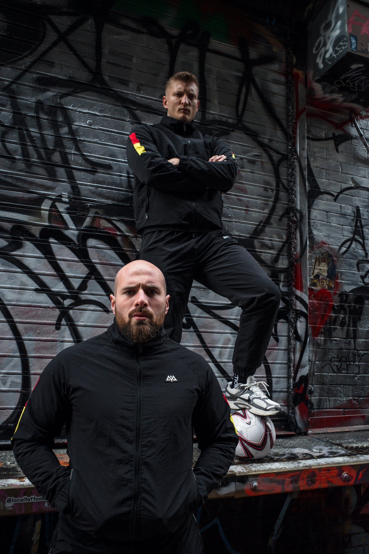 Schwarze Avantura Tracksuits mit rot-goldenen Details, Graffiti Hintergrund