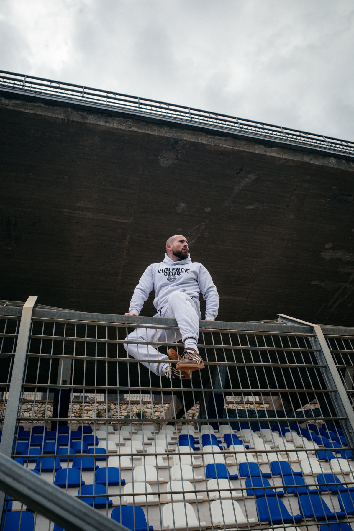 Grauer VIOLENCE CLUB Hoodie mit Brustlogo im urbanen Setting