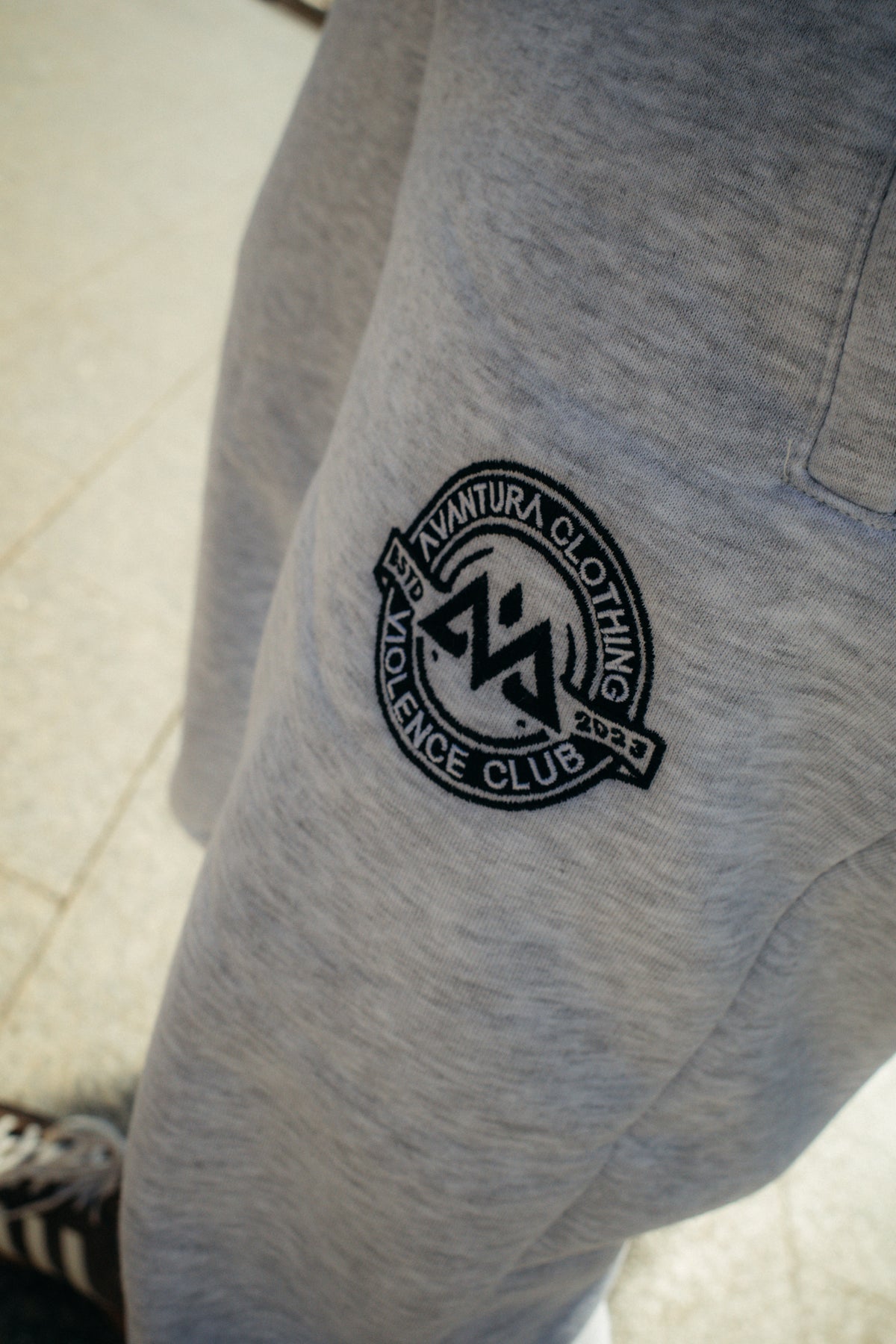 Nahaufnahme gesticktes Logo auf grauer AVANTURA CLOTHING Jogginghose