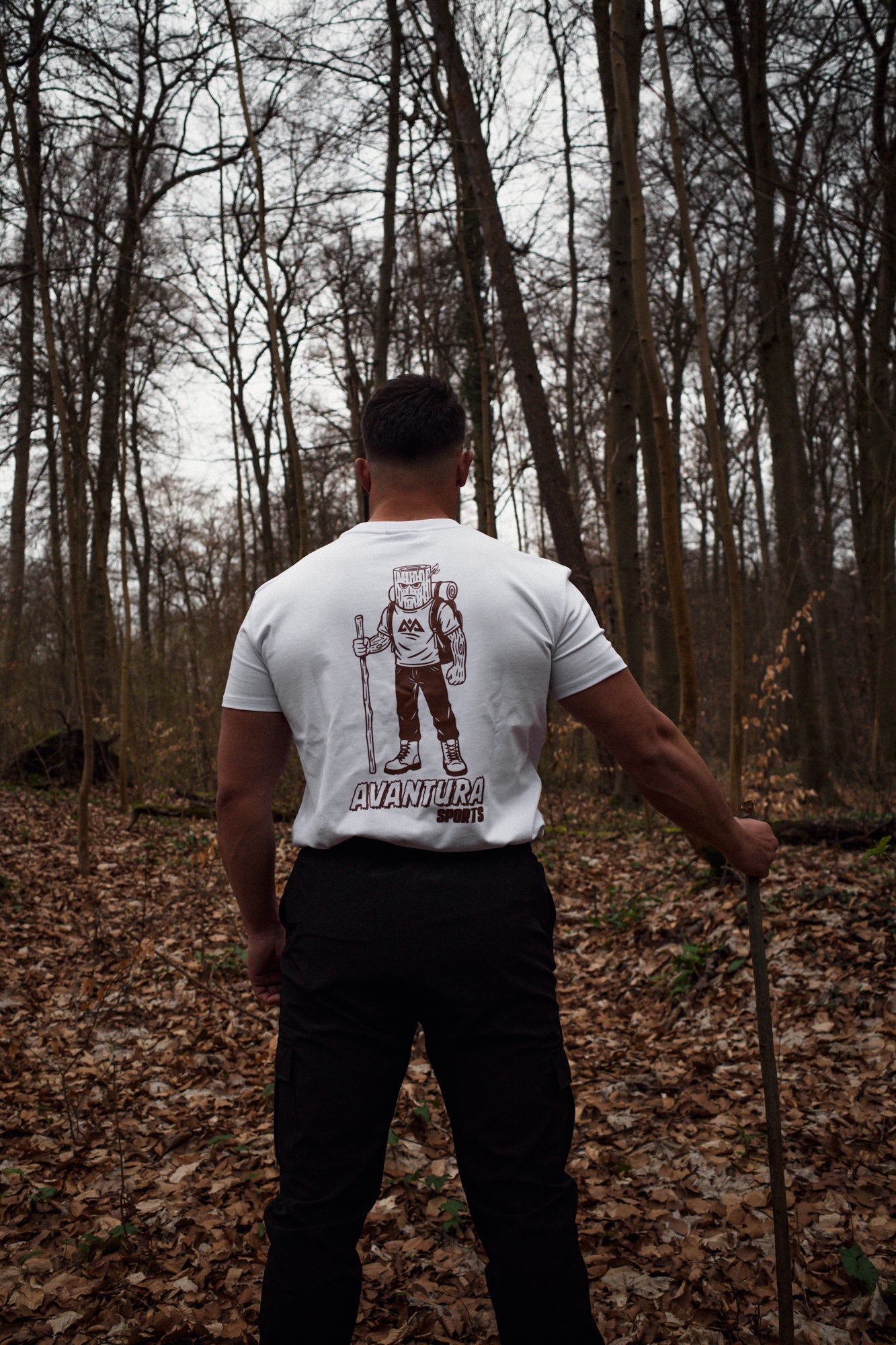 Back detail of white T-shirt showing cartoon hiker illustration and brand text