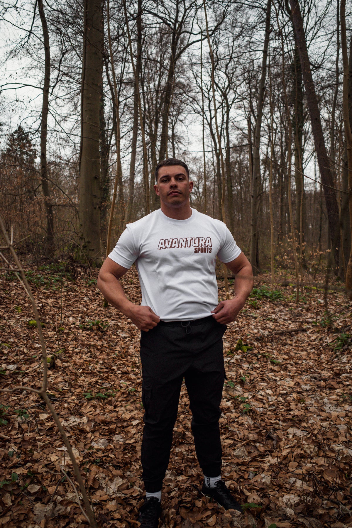 Close-up of white T-shirt front print with outlined AVANTURA and solid SPORTS text