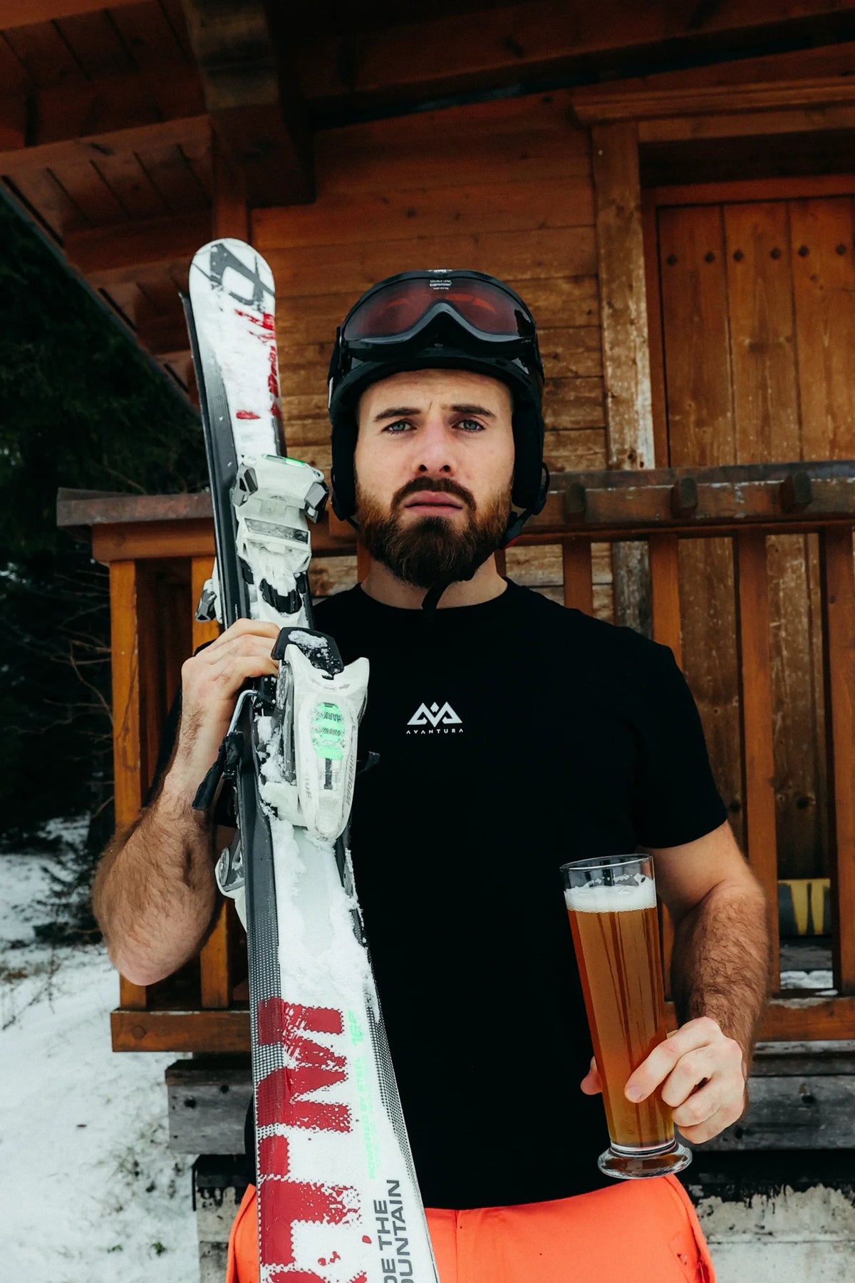 Men's black Avantura winter action T-shirt with white mountain logo on chest, worn skiing